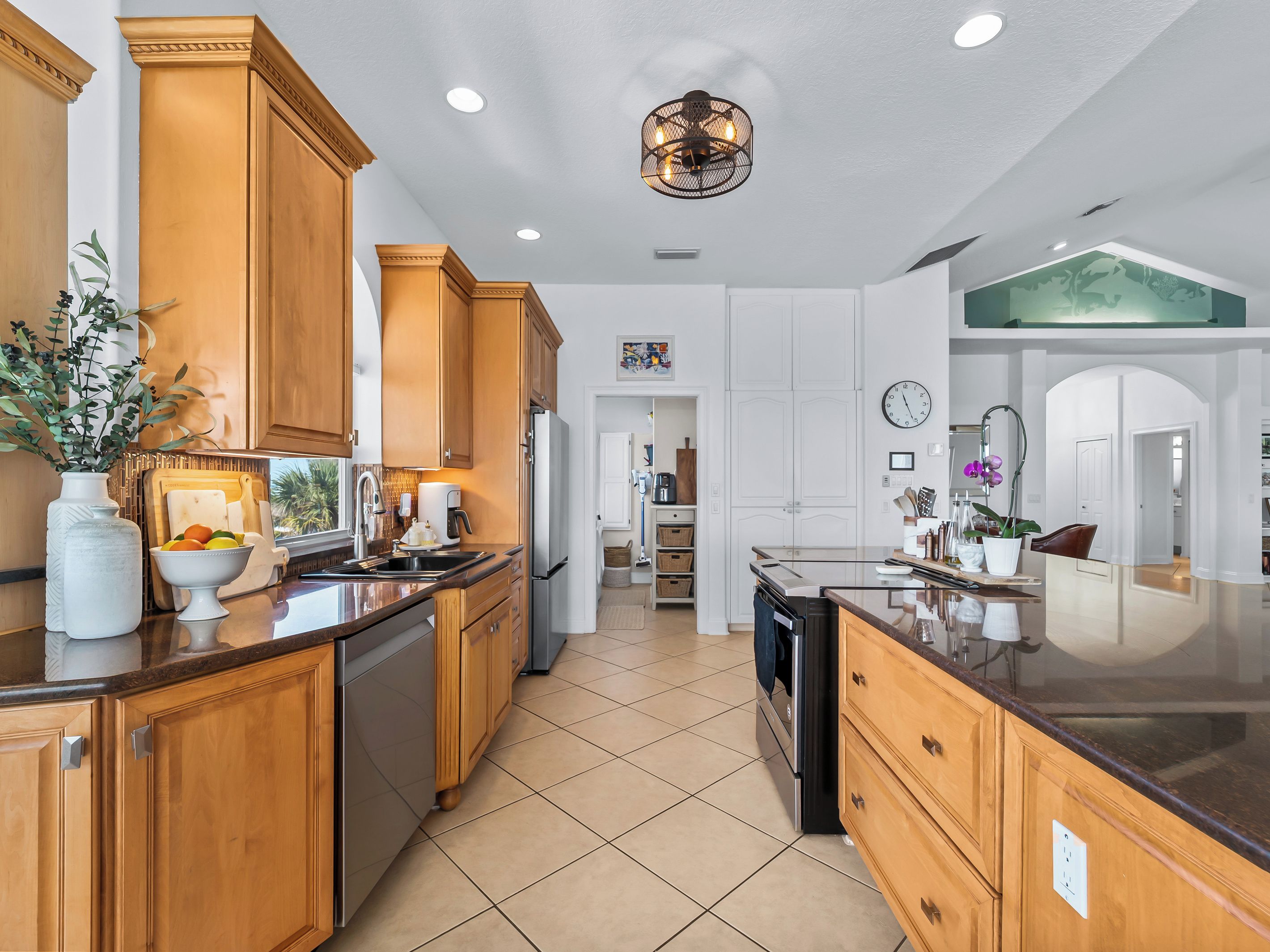 A modern kitchen with wooden cabinets, a central island, and a large window.