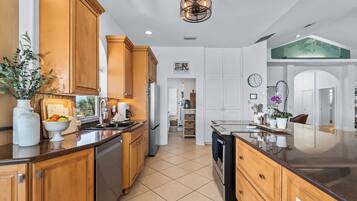 A modern kitchen with wooden cabinets, a central island, and a large window.