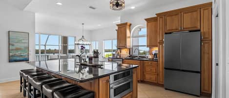 A spacious kitchen with a large island, wooden cabinets, and a stainless steel refrigerator.
