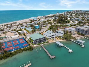 An aerial view of a coastal residential area with a tennis court, a marina, and houses with various architectural styles. - Bayfront home - Dock and Pool 3/3 (Englewood)