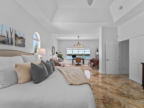 A spacious bedroom with a large bed, a desk, and a view of the outdoors. - Bayfront home - Dock and Pool 3/3 (Englewood)