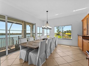 A spacious dining area with a view of the lake, large windows, and a modern kitchen. - Casa Bahia-Luxury Bayfront Pool Home with Dock (Englewood)