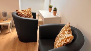 Ein modernes Wohnzimmer mit zwei schwarzen Sesseln, einem kleinen weißen Tisch und einem Oberlicht.