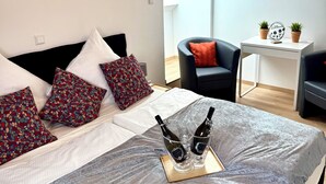 Ein modernes Schlafzimmer mit einem großen Bett, zwei Nachttischen, einem Sessel und einem kleinen Tisch mit Topfpflanzen.