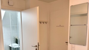 Ein modernes Badezimmer mit Duschkabine aus Glas, einer weißen Tür und einem Spiegel an der Wand.