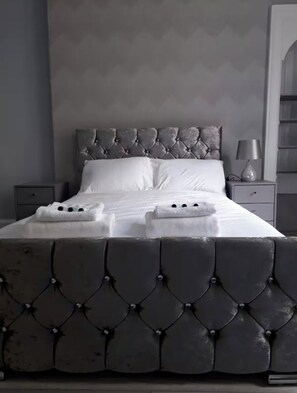 Ein Bett mit einem geblatteten Kopfteil, weißen Leinen und zwei Handtüchern darauf.