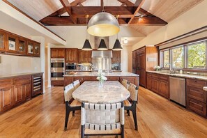 Une cuisine spacieuse avec des meubles en bois, un îlot central et une grande table à manger.