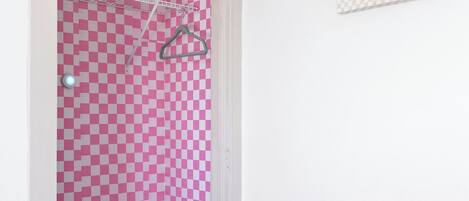 A bedroom with a checkered bedspread, a pink and white checkered door, and a motivational poster on the wall.