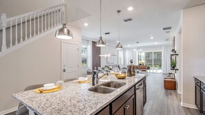 Una cocina moderna con encimeras de granito, electrodomésticos de acero inoxidable e iluminación colgante.