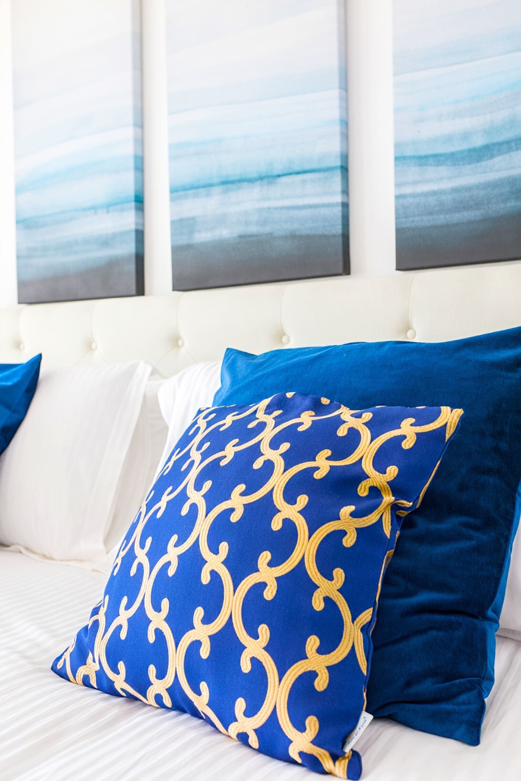 Una cama con ropa de cama azul y blanca, una almohada estampada en azul y una almohada blanca.