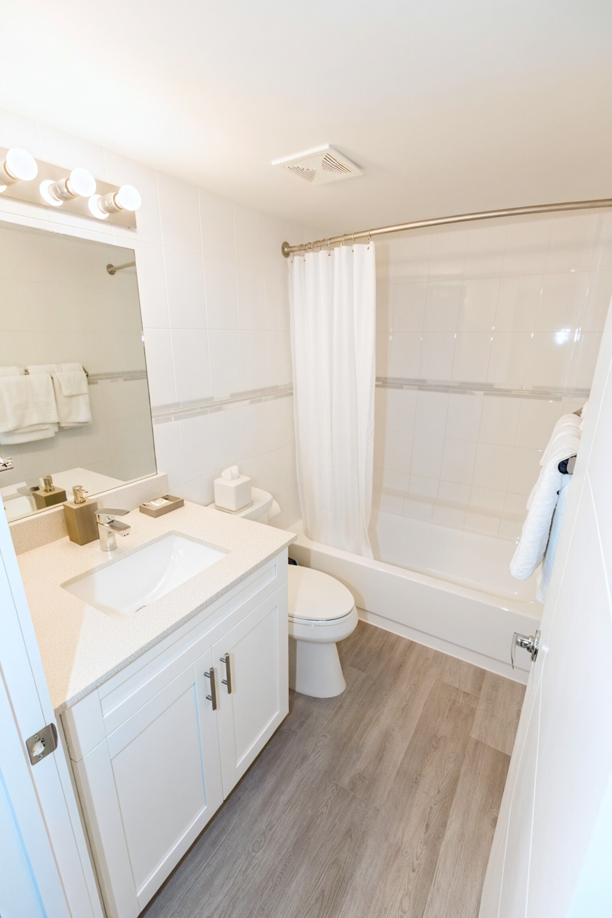 Un baño moderno con lavamanos, inodoro y ducha.