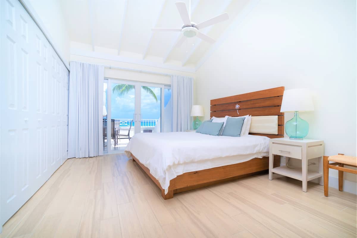 Un dormitorio con cama de madera, mesita de noche, ventilador de techo y vistas al exterior.