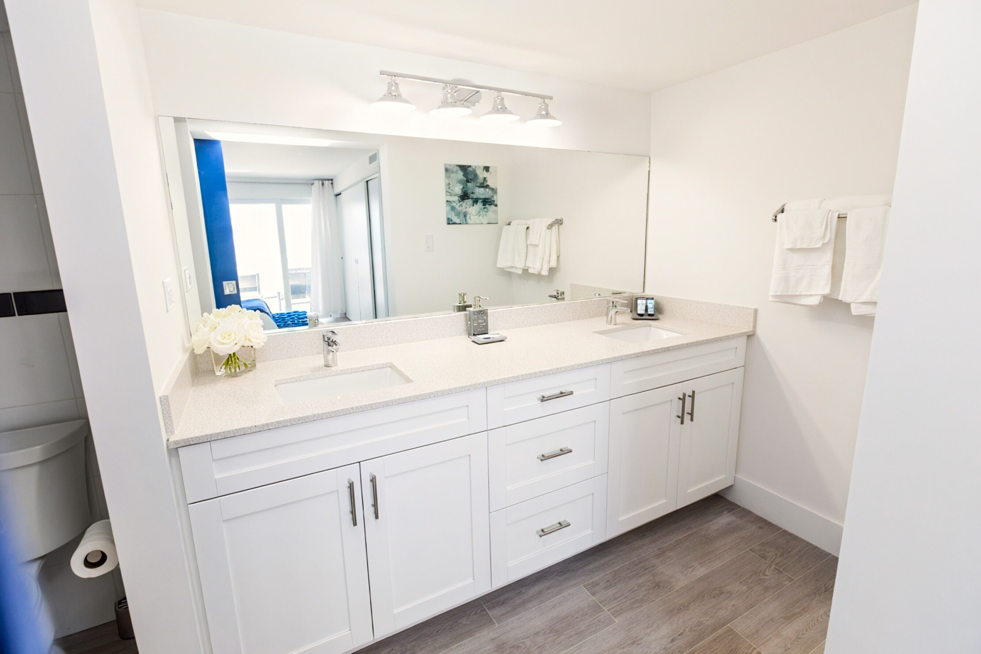 A modern bathroom with white cabinetry, a double sink vanity, and a large mirror.
