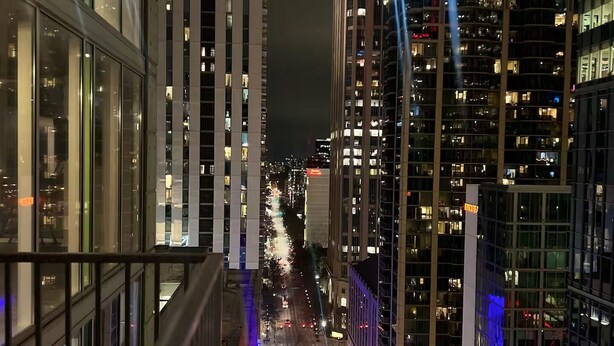 A nighttime cityscape with modern high-rise buildings, a busy street, and a clear view of the city skyline.