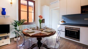 A modern kitchen with white cabinets, a built-in oven, and a dining area with a round table and chairs. - Apartments Florence I Portici (Firenze)