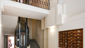 A staircase leading to a balcony with a metal railing, a wall-mounted storage unit, and a door at the bottom of the stairs. - Apartments Florence I Portici (Firenze)