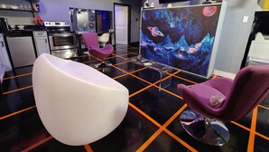A modern kitchen with a black and orange floor, a large flat-screen TV, and a space-themed mural. - StarLab '86 -Downtown Pet Friendly (Fort Smith)