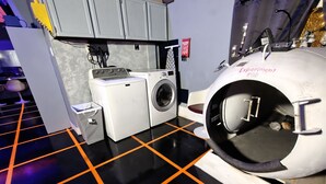 A room with a large cylindrical machine labeled "Experiment POD" and a washing machine. - StarLab '86 -Downtown Pet Friendly (Fort Smith)