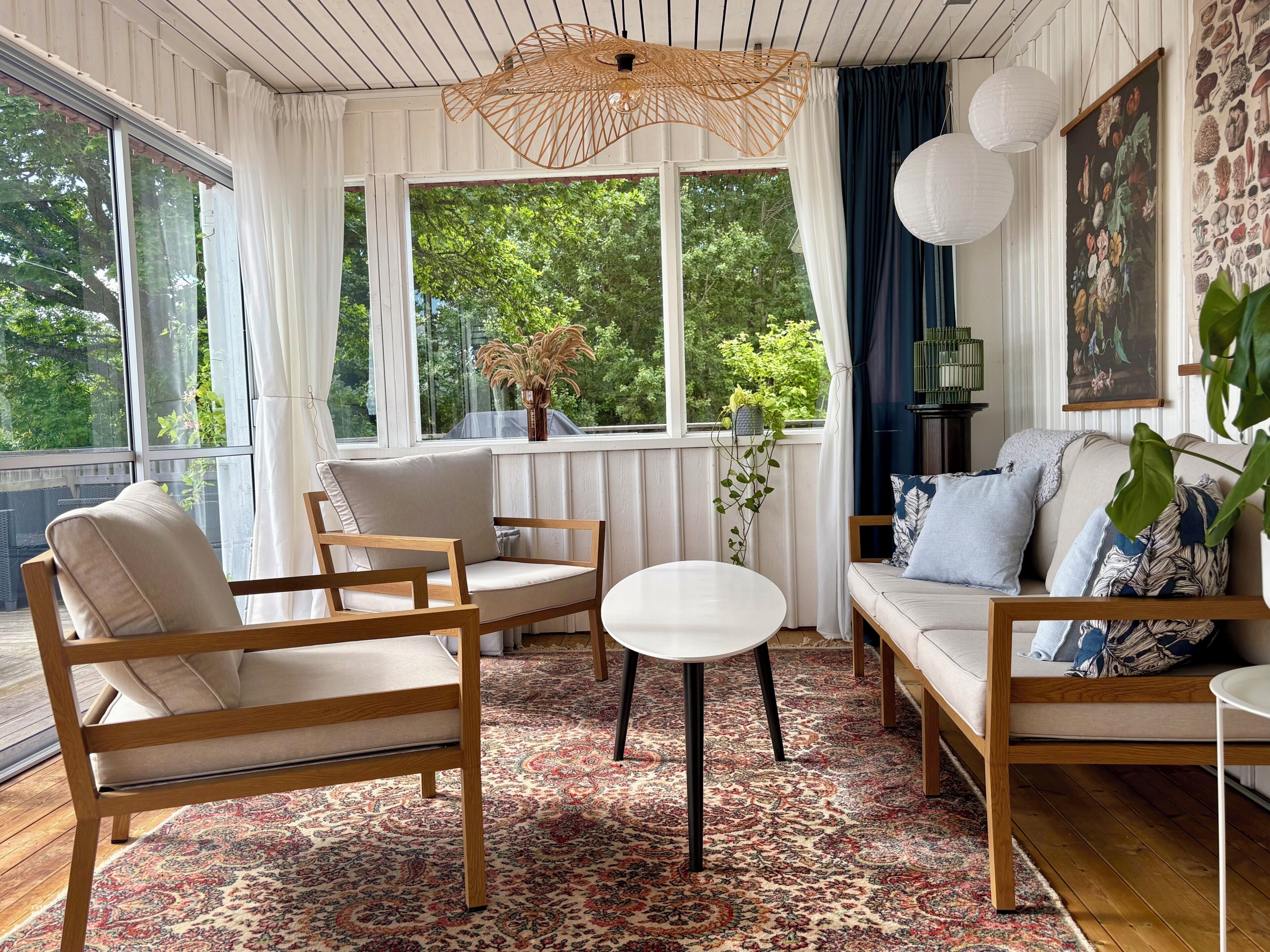 A cozy living room with a sofa, chairs, a small table, and a large window with curtains.