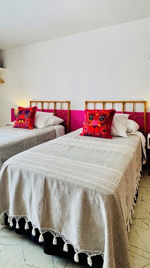 Two twin beds with patterned bedding, a wooden headboard, and a white wall. - Tropical Mid-Century Modern B&B in Centro, La Habitacion Rosa (Mérida)