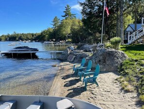 Enjoy a serene lakeside retreat with a clear view of the water, surrounded by lush greenery and a charming outdoor seating area.