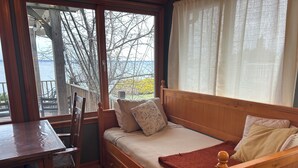 A cozy room with a wooden bed, a small table, and a chair. - Cozy Lake House on Oneida with Waterfront Access (Cicero)
