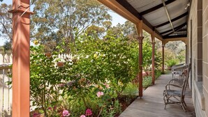A covered outdoor area with a wooden deck, potted plants, and a pergola structure. - Idyllic, peaceful and historical "Coath Cottage" minutes from Bendigo's CBD (West Bendigo)