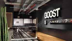 Un interior moderno con un llamativo letrero 'BOOST', una recepción y un adorno de bambú.