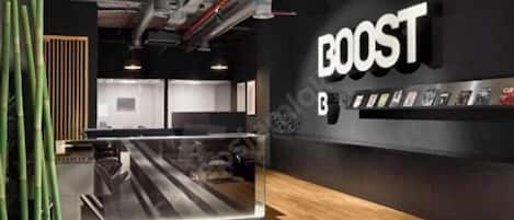 A modern interior with a prominent 'BOOST' sign, a reception desk, and a bamboo decoration.