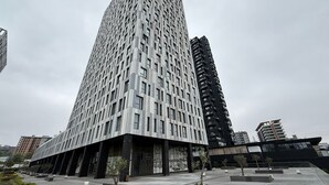 Un edificio moderno de gran altura con fachada de diseño geométrico, amplias ventanas y tejado plano.