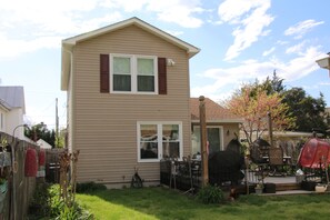 Ein zweistöckiges Haus mit Vorgarten, einer Terrasse und Gartenmöbeln sowie einem Grill.