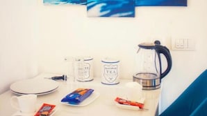 A room with a white table, a kettle, a coffee maker, and a tea kettle. There are two cups and a plate on the table. - Lumiere Luxe Suites (Belgrade)