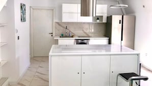 A modern kitchen with white cabinets, a marble countertop, and stainless steel appliances. - Lumiere Luxe Suites (Belgrade)