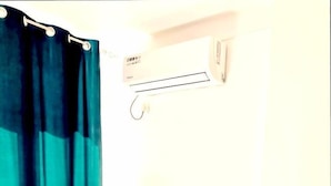 A small, modern bedroom with a white desk, a chair, a small trash bin, and a blue curtain. - Lumiere Luxe Suites (Belgrade)