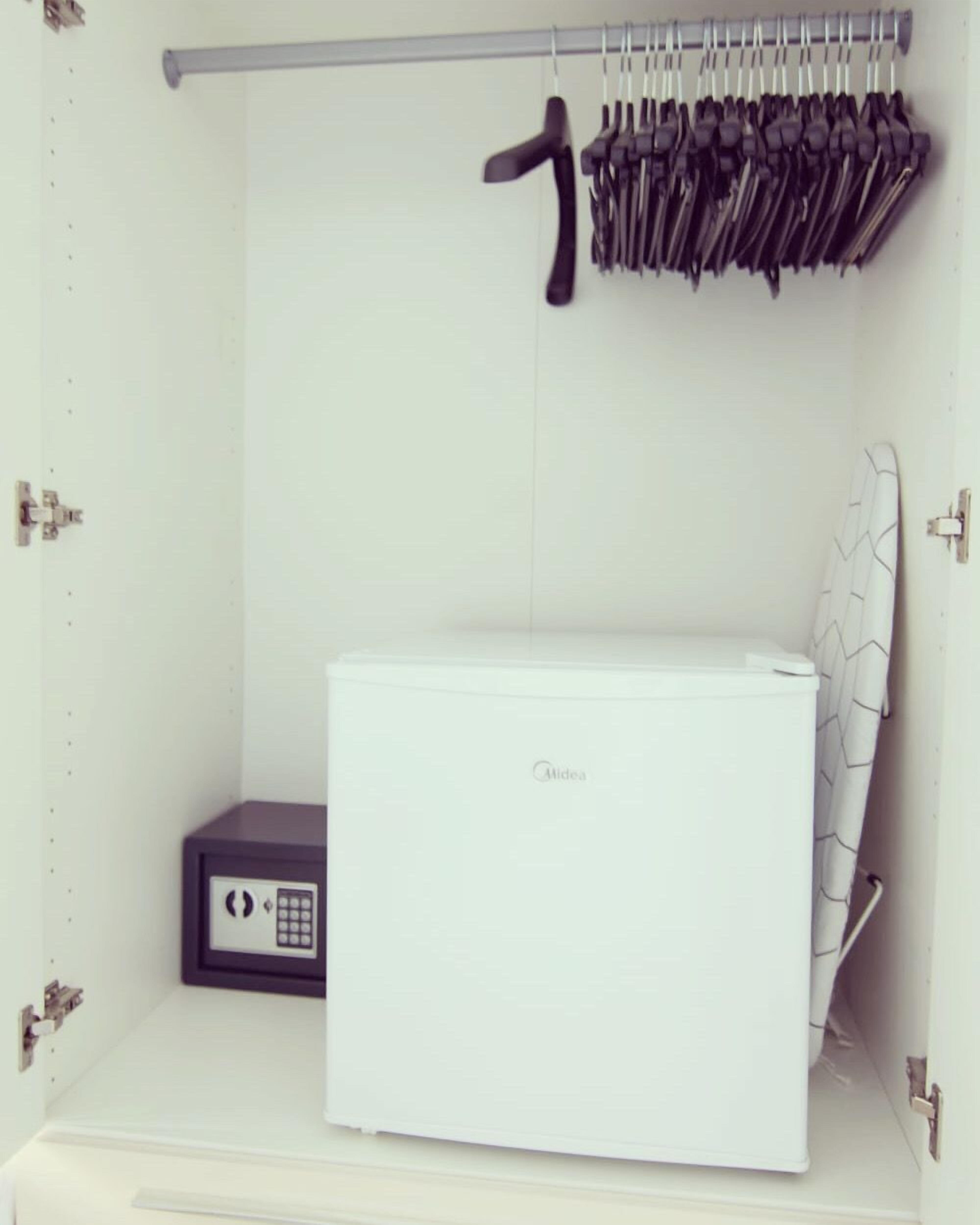 A compact storage unit with a white appliance, a small electronic device, and a metal rack with tools.