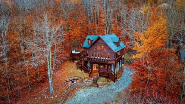 A large log cabin with a wrap-around porch, surrounded by autumn foliage. - Long Range Views Hot Tub Private FirePit Kid Bunks (Beech Mountain)