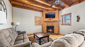 A cozy living room with a fireplace, wooden ceiling, and a television mounted above it. - Long Range Views Hot Tub Private FirePit Kid Bunks (Beech Mountain)