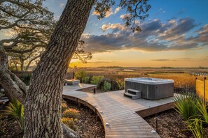 Una terraza de madera con un jacuzzi, rodeada de árboles y vistas al paisaje.