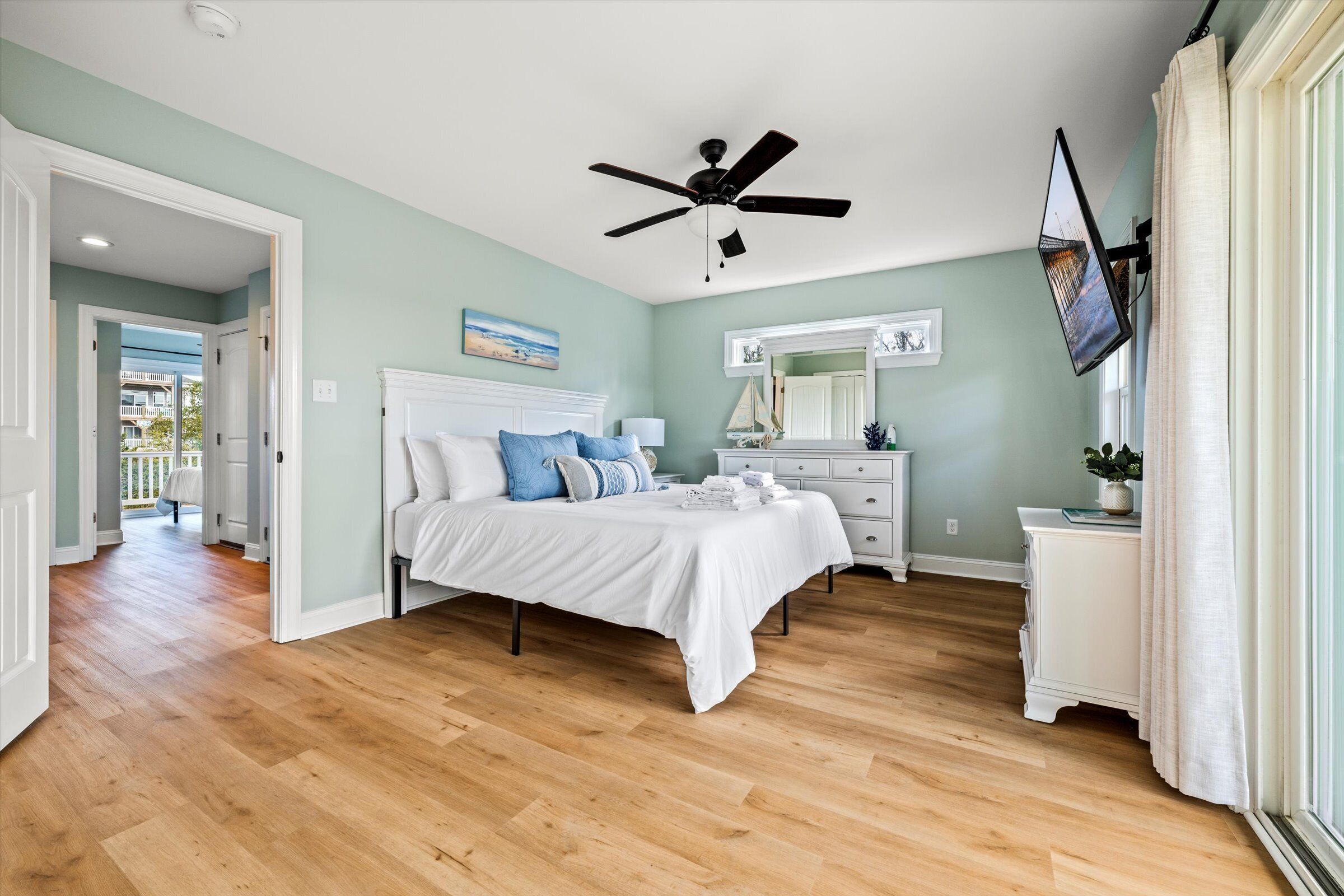 A bedroom with a bed, a ceiling fan, a TV, and a dresser.