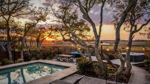 Un espace piscine doté d’une terrasse en bois, de chaises longues et d’un jacuzzi.