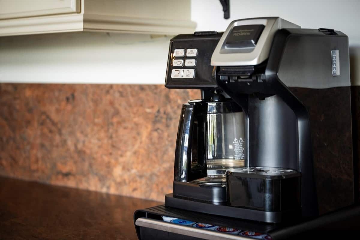 Eine Kaffeemaschine mit digitalem Display und Bedienfeld, auf einer Arbeitsplatte mit Granitverkleidung platziert.