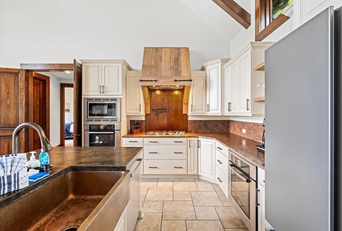 A modern kitchen with white cabinetry, a stainless steel sink, and a built-in oven.