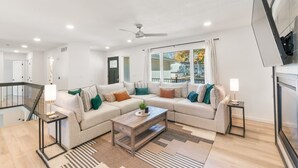 A modern living room with a sectional sofa, a coffee table, and a TV mounted on the wall. - Clear Lake Escape - Lake Views, Pool Table, Ping Pong Table, Fire Pit (Clear Lake)