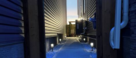 Un sentier bordé de bâtiments aux poutres en bois, avec un ciel dégagé au-dessus.