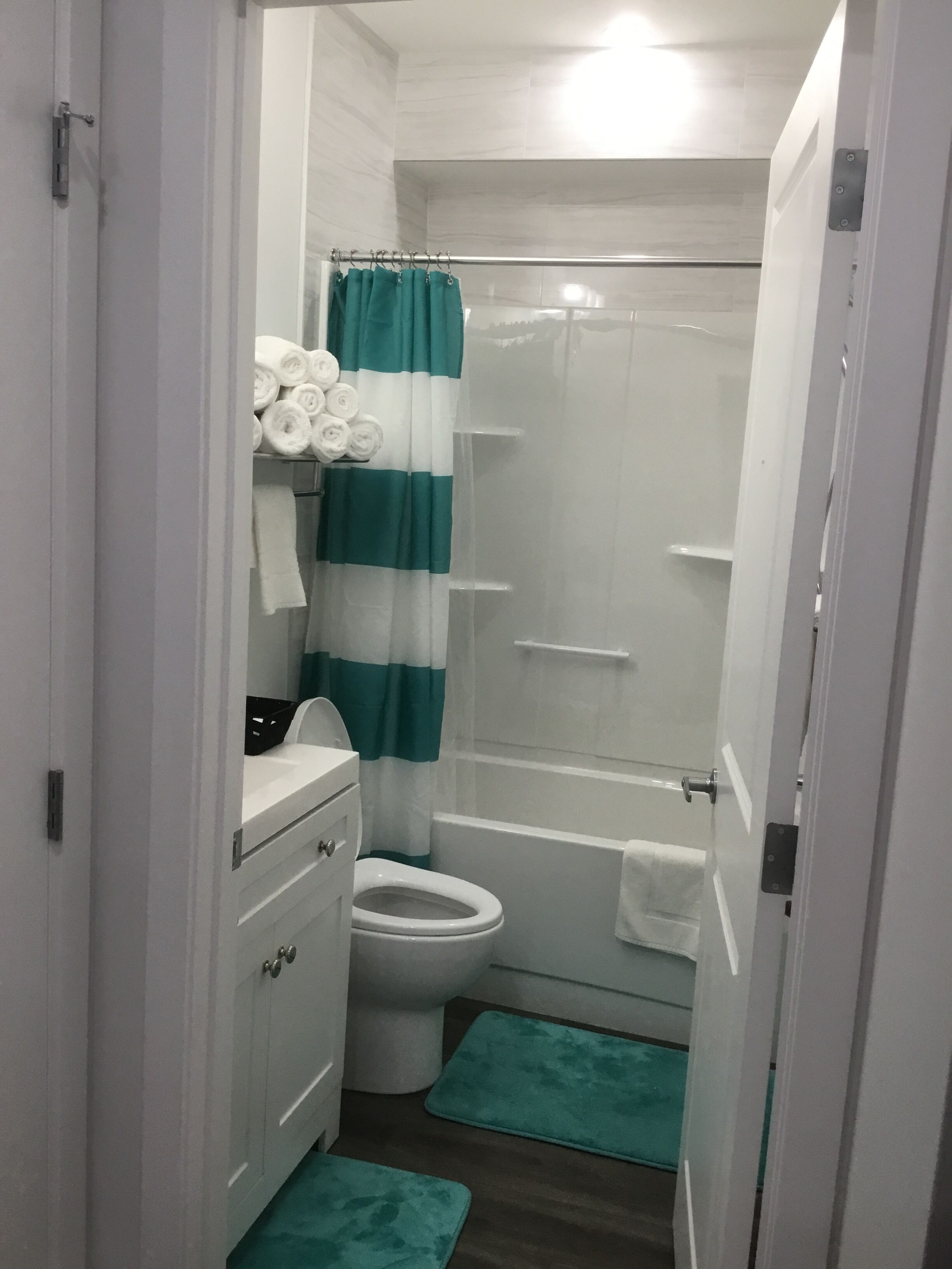 Une petite salle de bain avec des toilettes, une douche et un lavabo. On y trouve des serviettes et un rideau de douche.