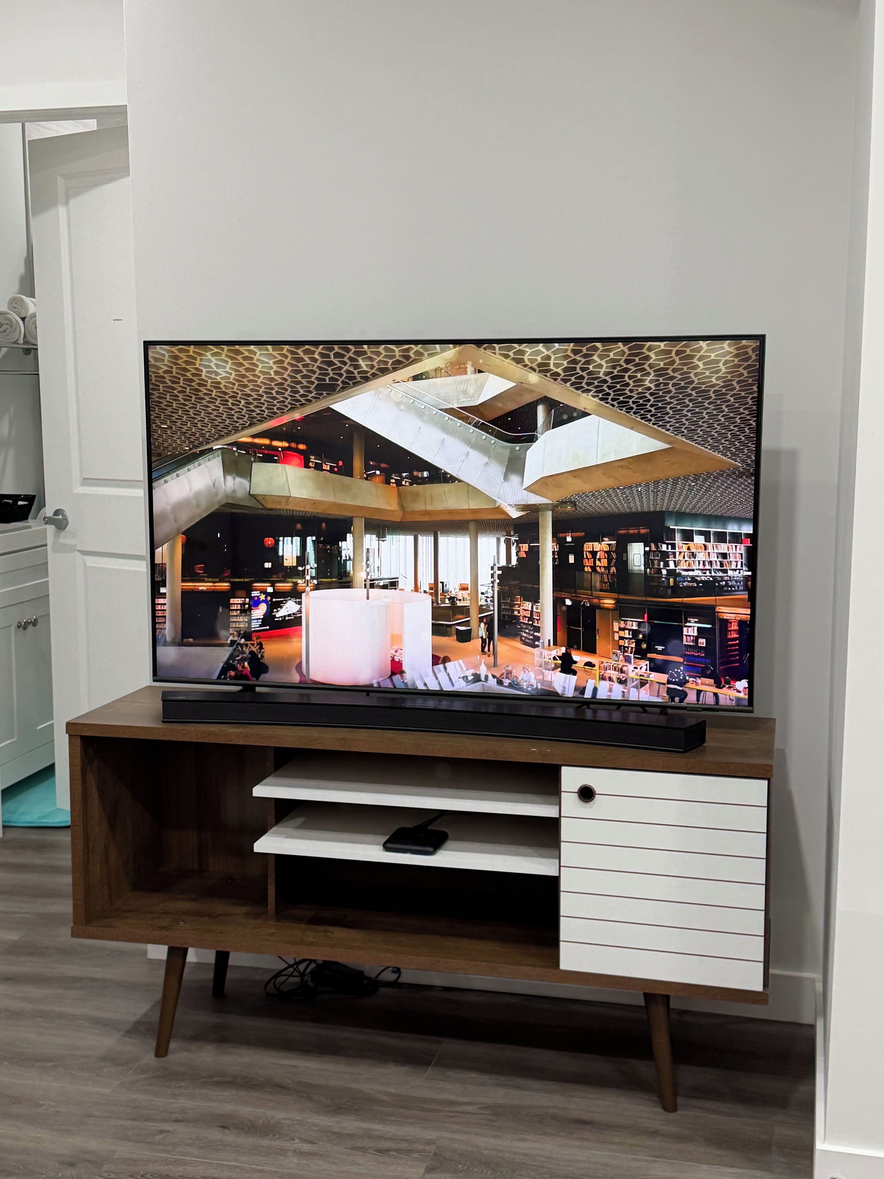 Un televisor de pantalla plana sobre un soporte de madera con un cajón blanco debajo.