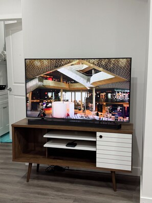 Een flatscreen televisie op een houten standaard met een witte lade eronder.