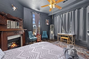 A bedroom with a fireplace, a bed, a desk, and a chair.