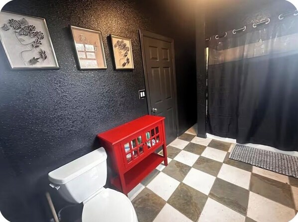 A bathroom with a white toilet, a red cabinet, and a black door.