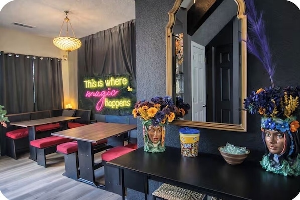 A modern interior with a neon sign, seating, a mirror, and decorative vases.
